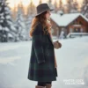 Mujer sonriente de perfil caminando por un sendero nevado, con una cabaña de madera rústica y árboles cubiertos de nieve al fondo. Viste un abrigo largo de cuadros escoceses en tonos verde y azul, un sombrero de fieltro gris oscuro, bufanda beige y guantes de punto marrón.