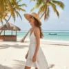 Mujer joven caminando alegremente de perfil por una playa de arena blanca, vistiendo un vestido blanco corto y un sombrero de paja de ala ancha. Al fondo se ven palmeras, un mar turquesa y una pequeña embarcación.